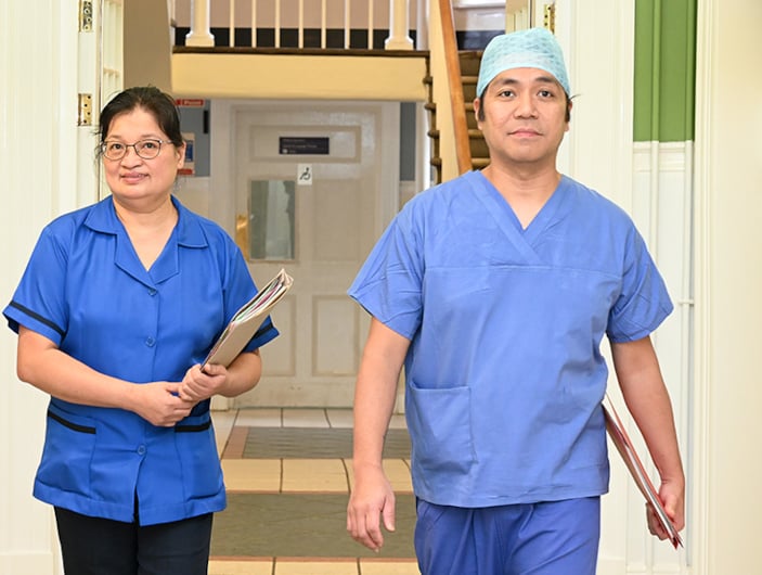 Two INMO members in blue scrubs walking down a hospital corridor